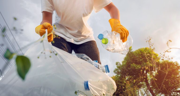 Volunteer teenage boys picking plastic bottle waste at public parks.