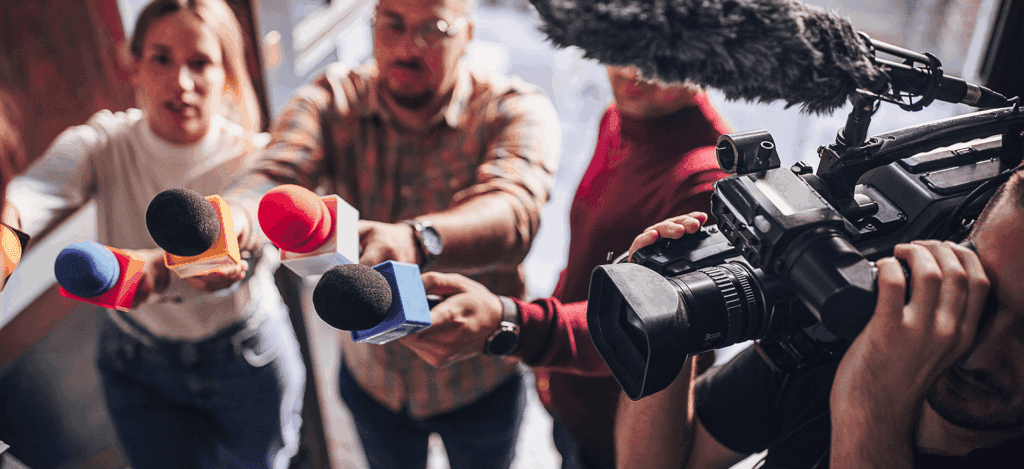 Group of people, female politician confronted by journalists with microphones.