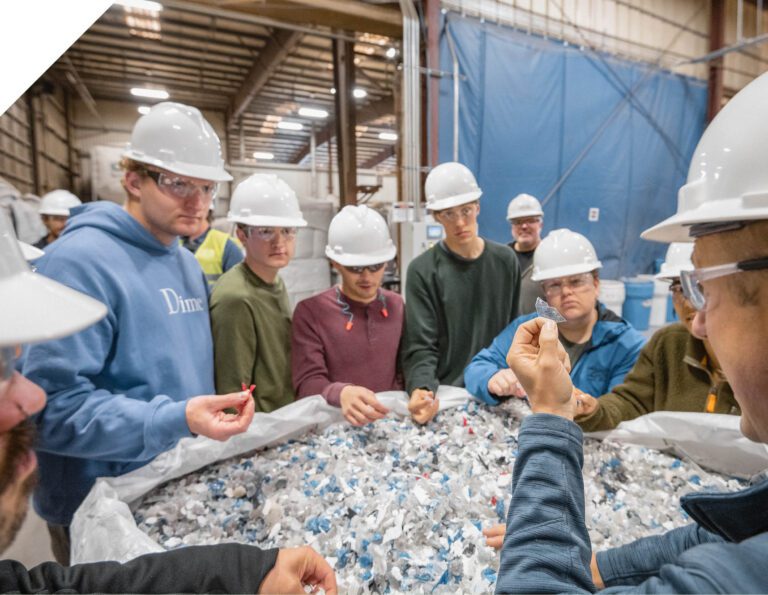 Agilyx employee and students looking at feedstock.